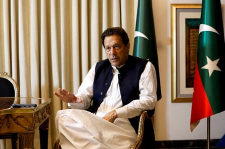 Khan dressed in white shalwar kameez, sitting, speaking to an interviewer off camera.