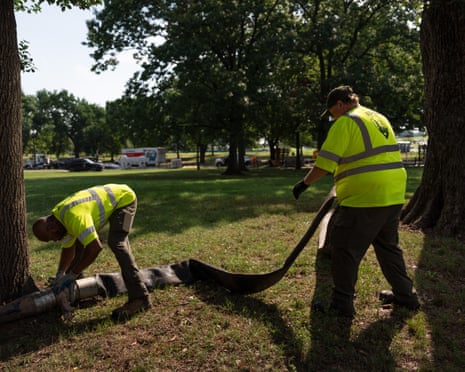 National Park Service workers unroll a length of hose near the World War II Memorial.