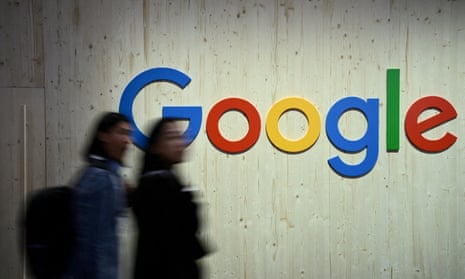 People walk next to a Google logo during a trade fair in Hanover