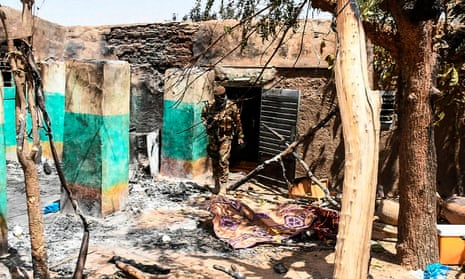 A soldier walking among rubble of a house destroyed during an attack on the village of Ogossagou, near Mopti, where over 130 Fulani villagers, including women and children, were killed.