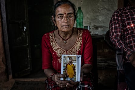 A woman sits indoors holding a photo of a man