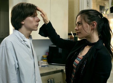 A boy in a blue shirt and a girl wearing a black top putting her hand on his head