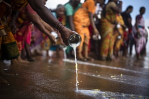 People pour milk in the waters of the Bay of Bengal as they pay homage to the victims during a prayer ceremony to mark the 18th anniversary of the 2004 Indian Ocean tsunami at Nochikuppam beach in Chennai
