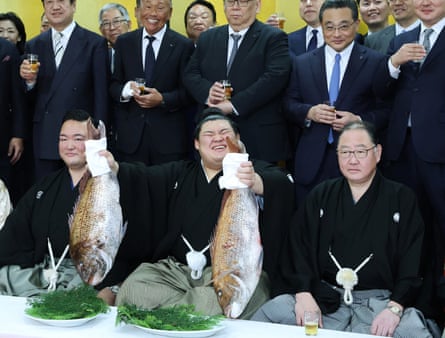 Onosato, center, holds up a fish as he celebrates after his yokozuna promotion ceremony on Wednesday in Ami Town, Ibaraki prefecture.