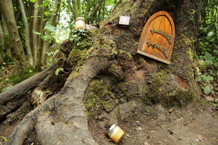 A historic arched door at the base of a tree, with jars of honey around the roots.