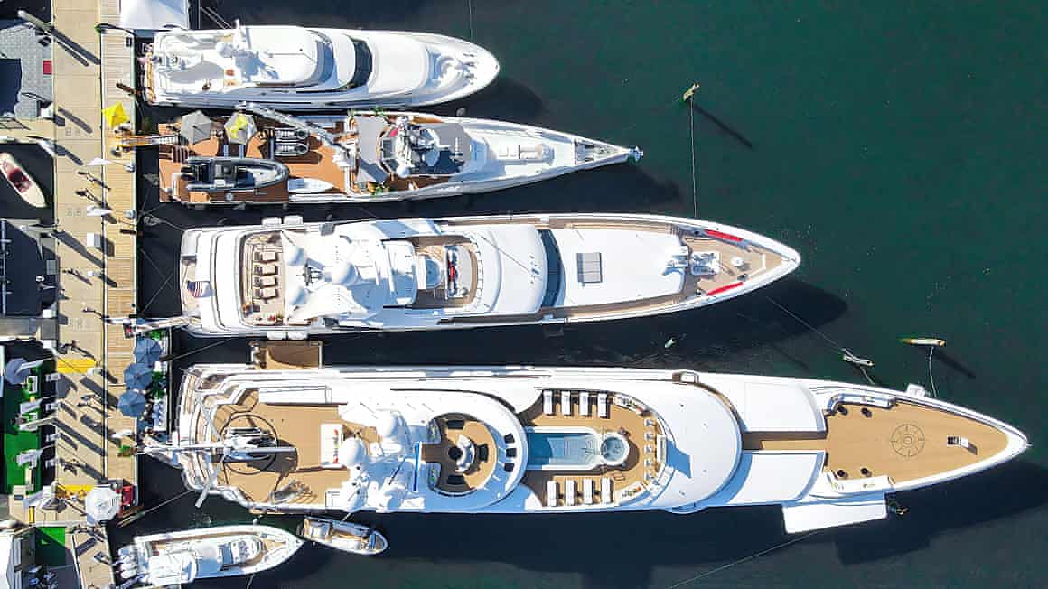 Drone view of four superyachts of different sizes moored alongside each other in a marina