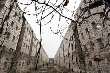 Concertina wire and vines line the stone walls of a former cell block at Sing Sing correctional facility.