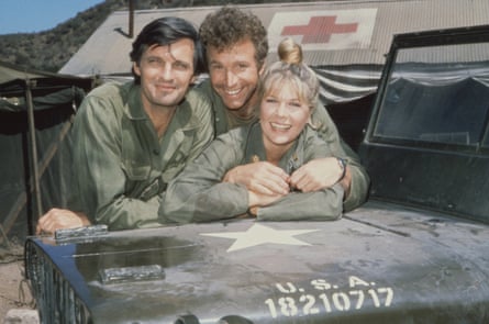 two men and a woman smile as they lean against an army Jeep marked USA