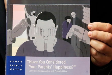 A hand holds a report titled Have You Considered Your Parents’ Happiness?: Conversion Therapy Against LGBT People in China