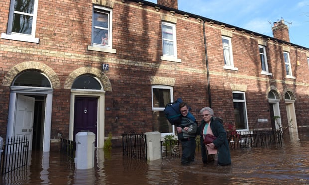 People walk down a flooded street in Carlisle, Cumbria