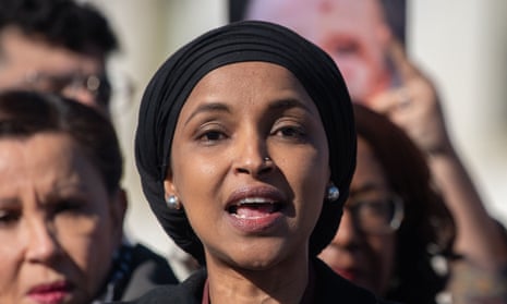 A Somali Muslim woman wearing a black headwrap speaks outside in a crowd.