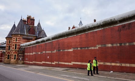 Two police officers walking outside the redbrick walls of HMP Manchester