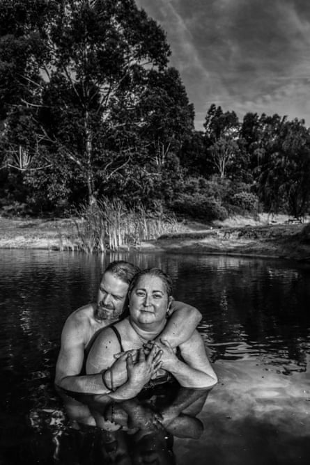 A woman embraced by a man stands in water in a black and white image