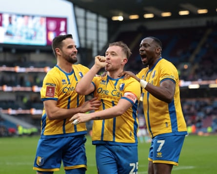 Louis Reed celebrates with teammates after scoring Mansfield’s winner at Burnley.