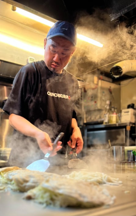 A chef cooks okonomiyaki on a griddle at Chinchikurin, a restaurant in Hiroshima, Japan