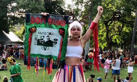Rio’s carnival, Rio de Janeiro. Stilts walker Liana Barros holds up a banner she made honouring British journalist Dom Phillips and Brazilian Indigenous expert Bruno Pereira, who were murdered in the Amazon last year.
