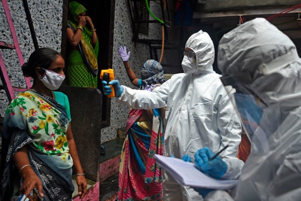 Medical volunteers take the temperature of a woman during door-to-door medical screening inside Dharavi, in Mumbai.
