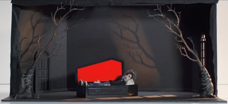 A puppet wearing a black suit is shown lying in a black coffin with a red lid in a still from André Is an Idiot.