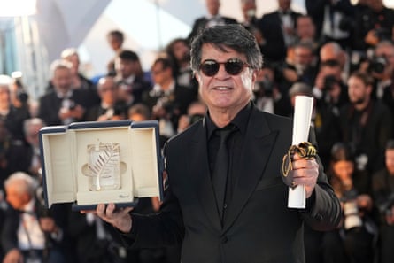 man in black suit smiles as he holds award