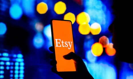 A smartphone users holds up a mobile with the Etsy logo on the screen