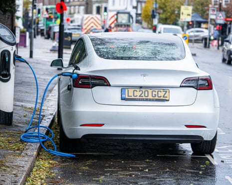 A white Tesla car plugged in to an electric charging point in London.