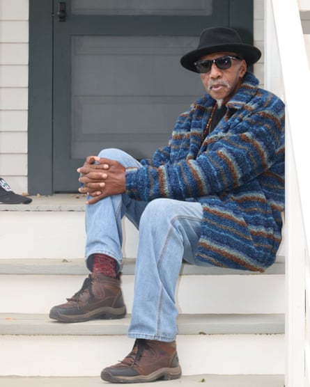 An older man sits on the stairs of a house.