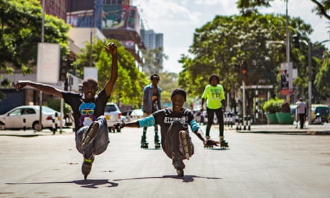 Michael Munge and Jesse Otumba practice a move between cars on a street in central Nairobi.