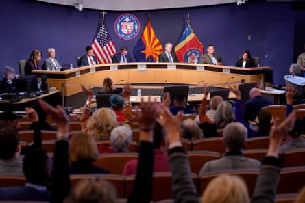 People wave their hands in silent disagreement as the Maricopa county board of supervisors conducts its general election canvass meeting on 28 November 2022 in Phoenix.
