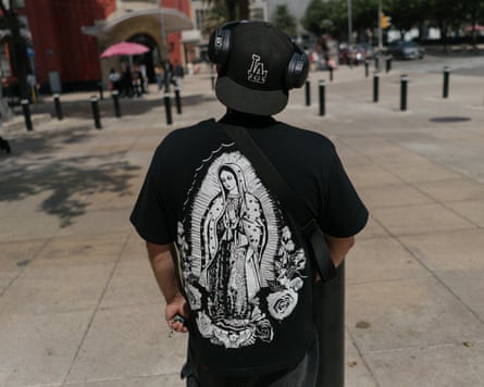 Man in black LA baseball cap and Virgin Mary T-shirt with back to camera