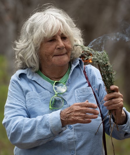 Sandra Saunders holds a smouldering bundle of herbs, smoke rising upward
