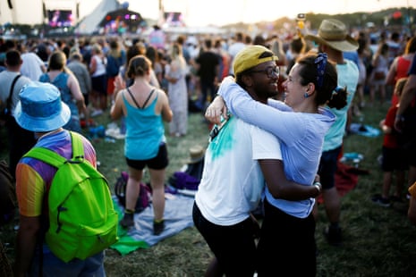 A couple embrace as the sun sets behind the Pyramid stage
