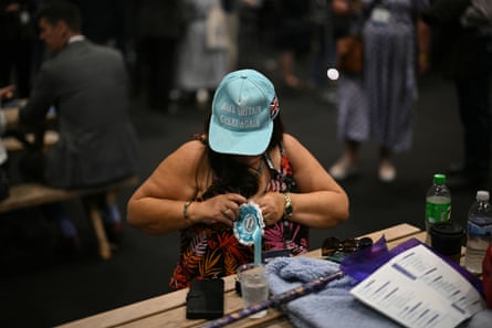 Woman in baseballl cap pinning on a rosette ar Reform UK party conference