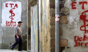 An old man walks past graffiti depicting the logo of Basque separatist group Eta in Goizueta