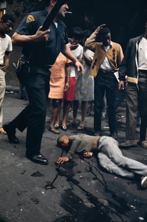 Joey Bass Jr lies wounded on the street as Officer Scarpone, one of the Newark policemen whose bullets hit him, stands over and people look on in dismay
