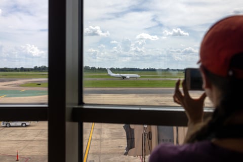 A woman observes an airplane from a window of observation deck at airport