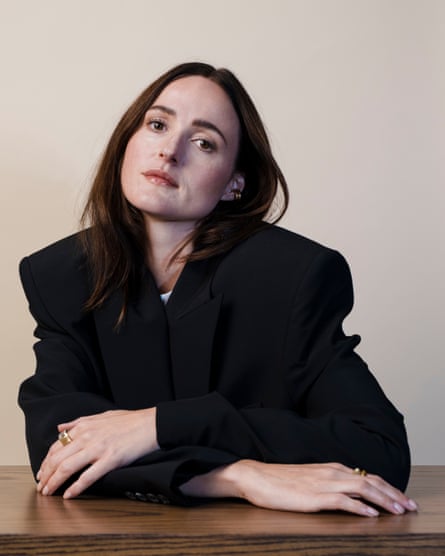 Renate Reinsve sitting at a table wearing a black jacket.
