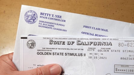 Close up of hand holding a Golden State Stimulus check sent out by the state of California