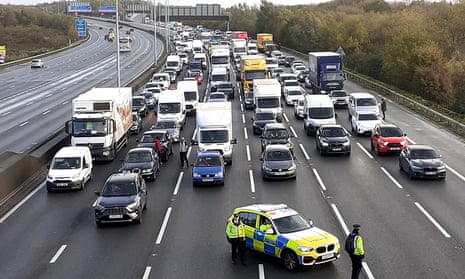 Photo issued by Just Stop Oil of police closing the M25, where a demonstrator, from Just Stop Oil, has climbed the gantry.