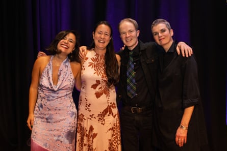 Four people with their arms around each other smile at the camera