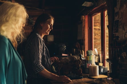 A woman weighs a burl while another woman watches besides her
