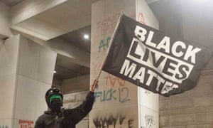 A protester holds up a Black Lives Matter sign in front of the Federal Courthouse in Portland on Saturday night