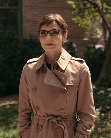 a woman in a trench coat stands outside for a portrait