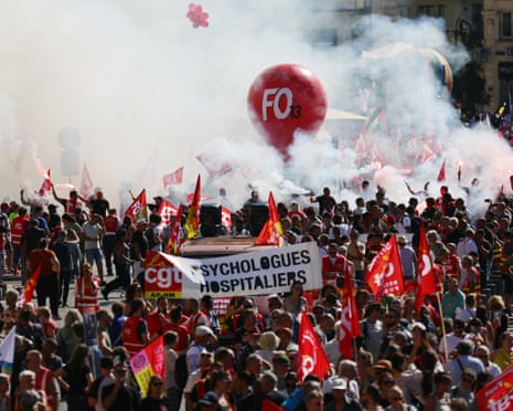 A large crowd with banners, a balloon and flares