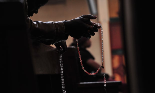 Person praying with a rosary.
