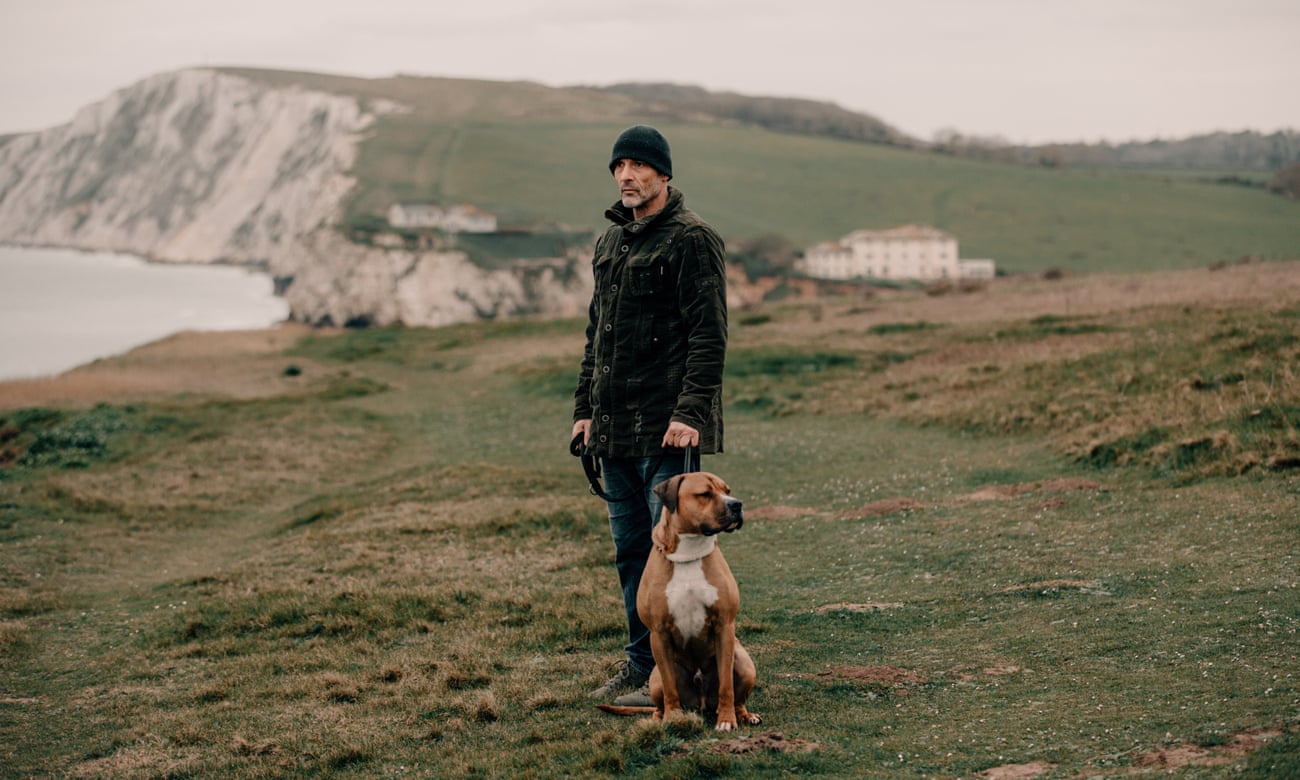 Daniel Payne, 45, who was convicted but is now out on licence, standing by a cliff with a dog.