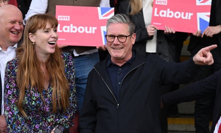 Keir Starmer and Angela Rayner laugh in front of people holding Labour placards