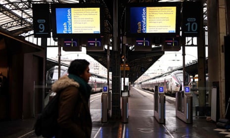 A passenger walks past a platform entrance with screens displaying a message during the shutdown at  Gare de l'Est