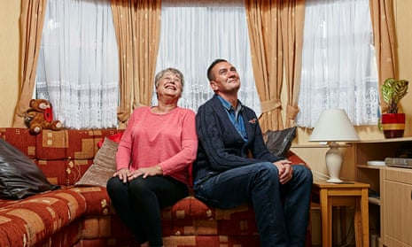 Jenny and Lee striking a pose side by side on a sofa in a living room, smiling and looking up at the ceiling