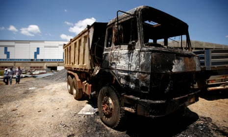 People walk near a torched truck damaged by protests in the town of Sebeta, Oromia region, Ethiopia