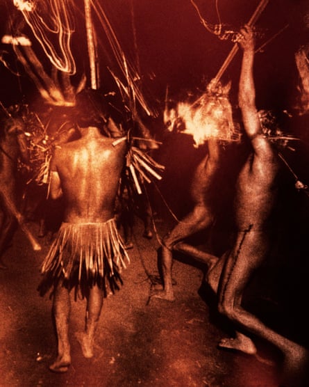 Blurred image of nude and semi-nude Yanomami people in traditional outfits amid flames